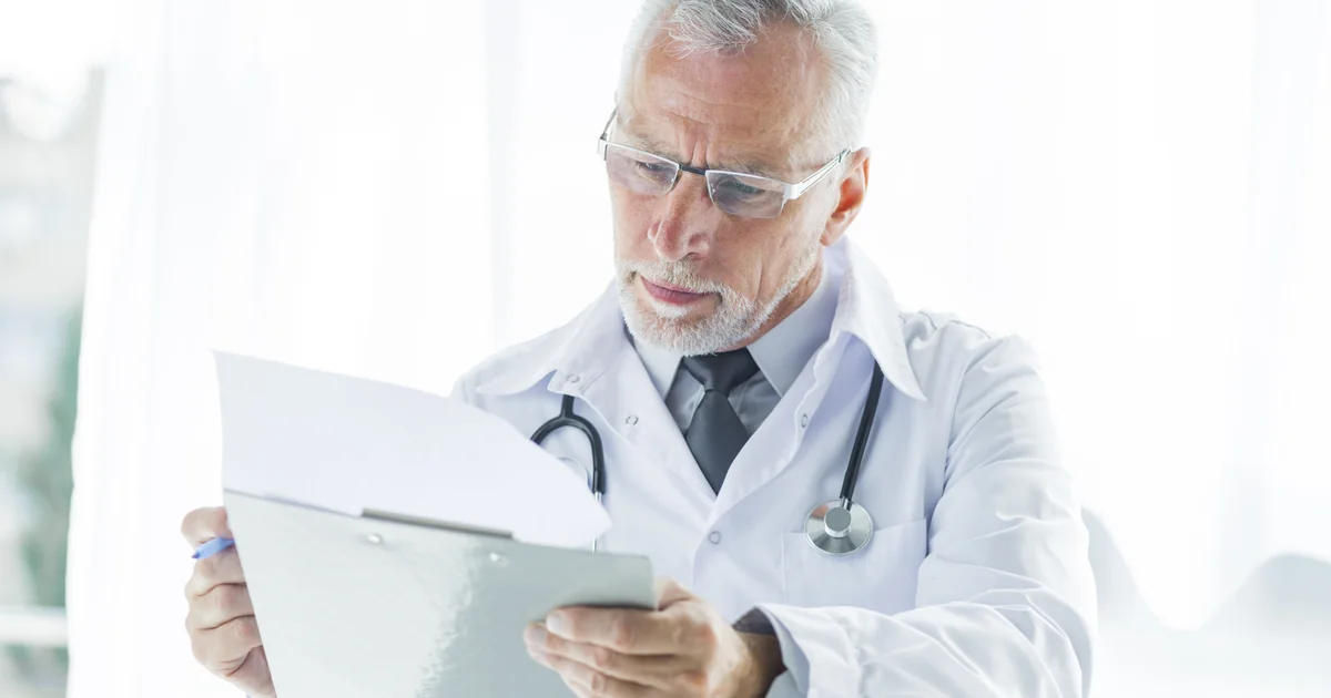 Médico analisando documentos tributários no consultório · Lucro Presumido Médico 2026 PleniHub